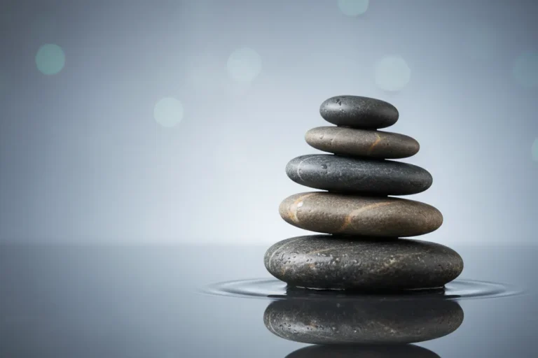Balanced stack of smooth stones on a reflective surface against a soft foggy background.